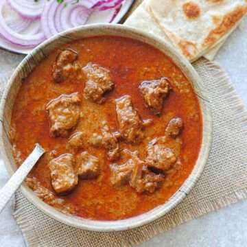 mutton korma in a dish with onions and Indian bread