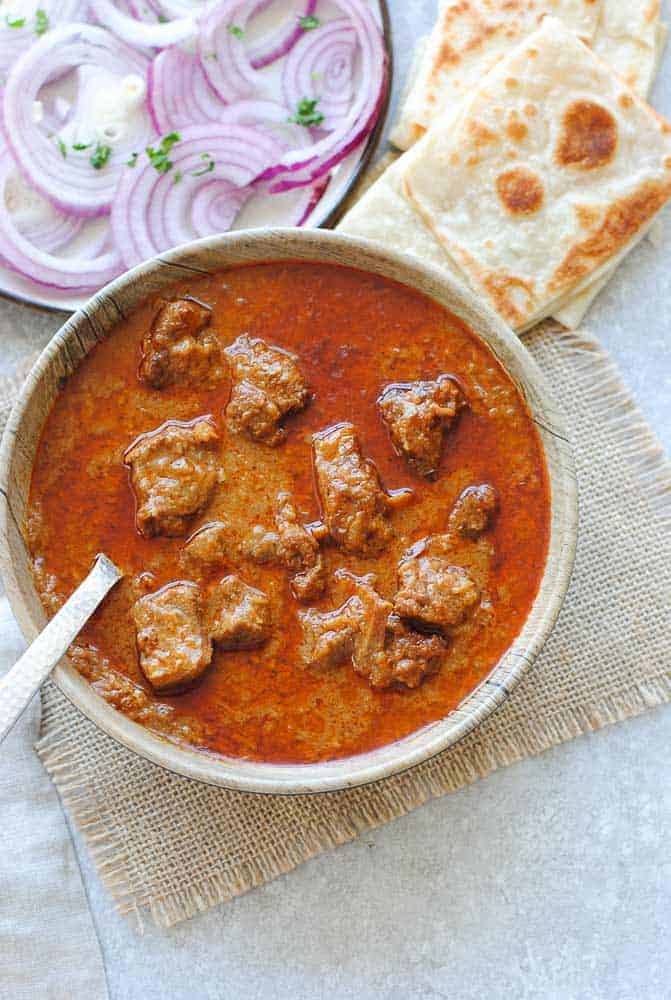 mutton korma in a dish with onions and Indian bread
