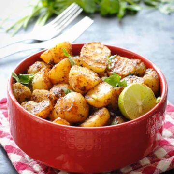 Aloo Chaat in (potato salad) in a bowl with cilantro and a lemon wedge
