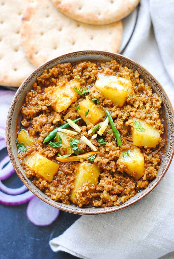 keema aloo in a bowl with naan and sliced onions on the side