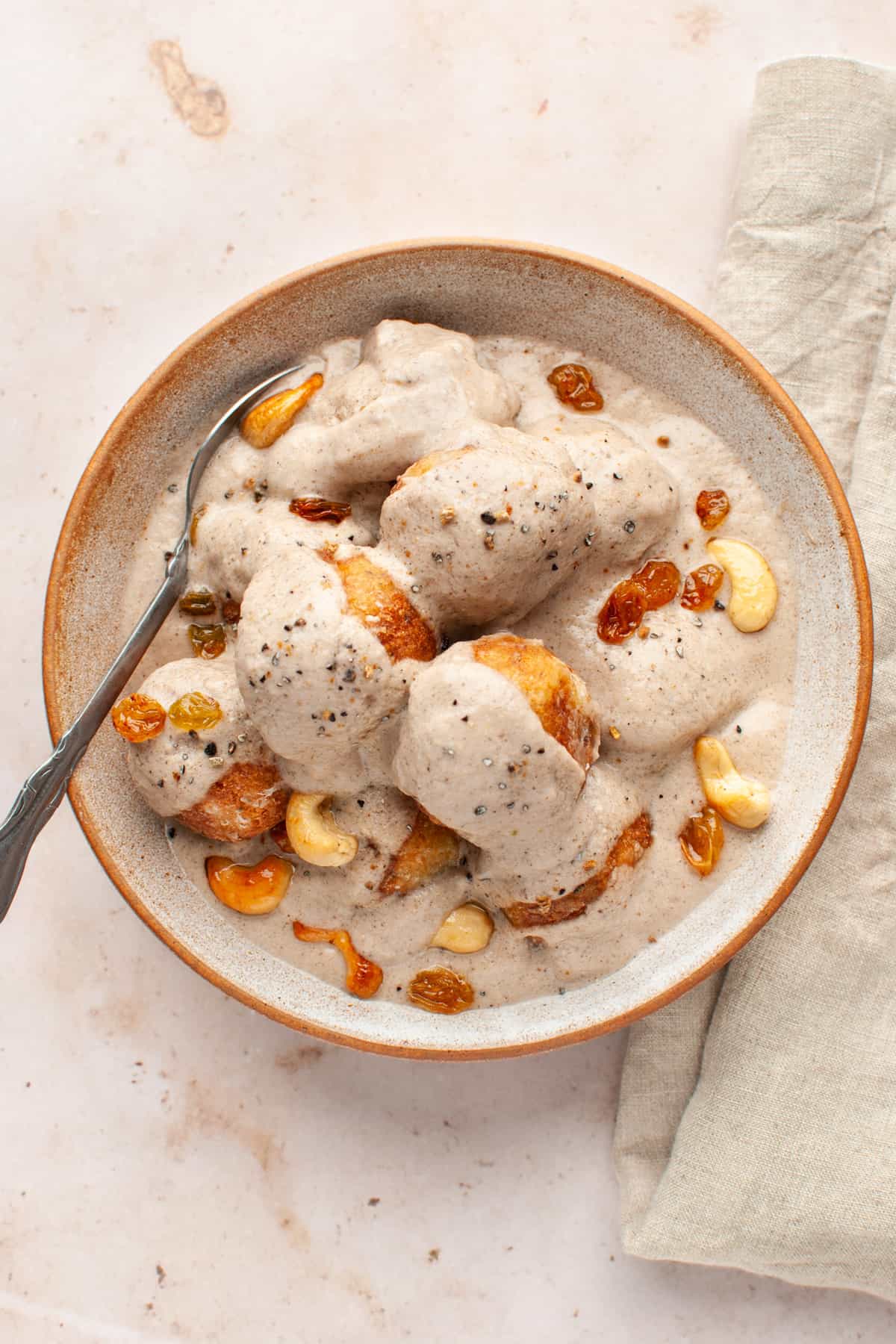 Sweet malai kofta gravy in white sauce in a bowl. 