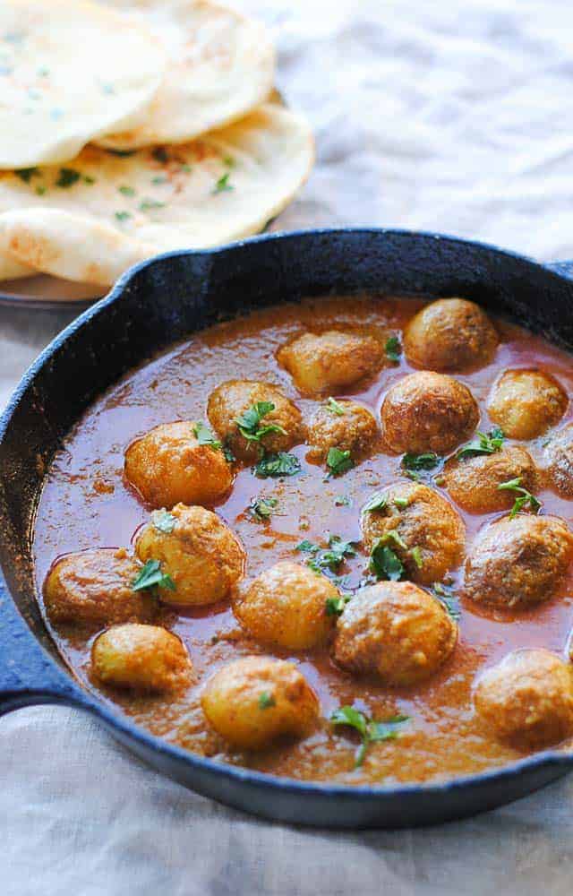 Dum aloo in a skillet with naan on the side