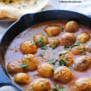 Dum aloo in a skillet with naan on the side