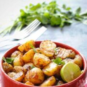 Aloo chaat (fried potato snack) in a bowl with cilantro and two forks