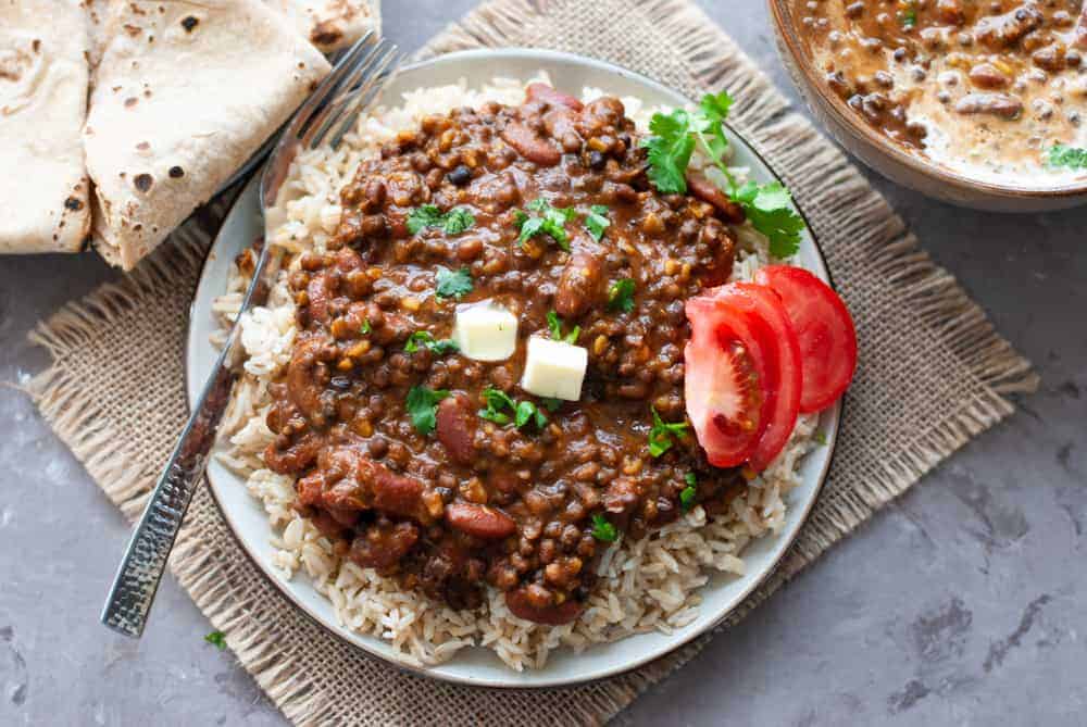 dal makhani in a bowl with a spoon of dal over it and naan in the background