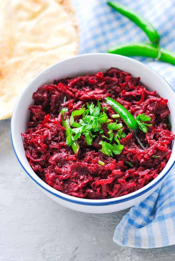 beetroot sabzi in a bowl with naan and green chillies on the side