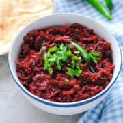 beetroot sabzi in a bowl with naan on the side