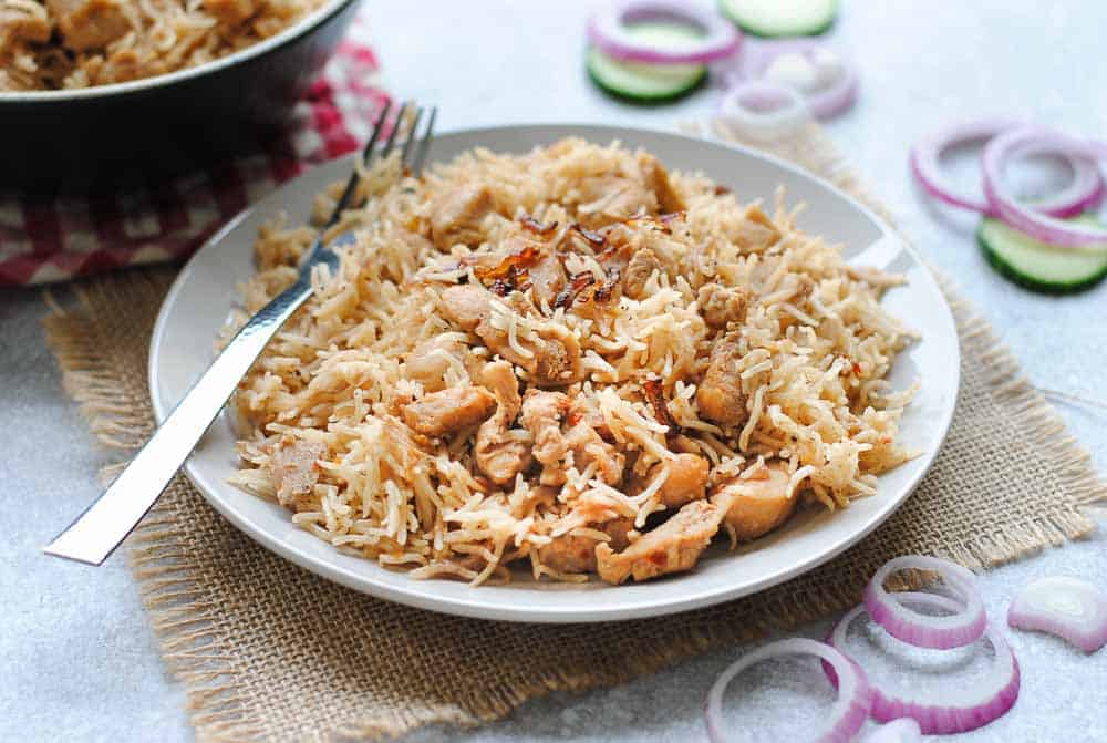 chicken pulao on white plate with a spoon