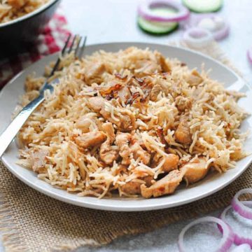 chicken pulao in a plate with onion rings