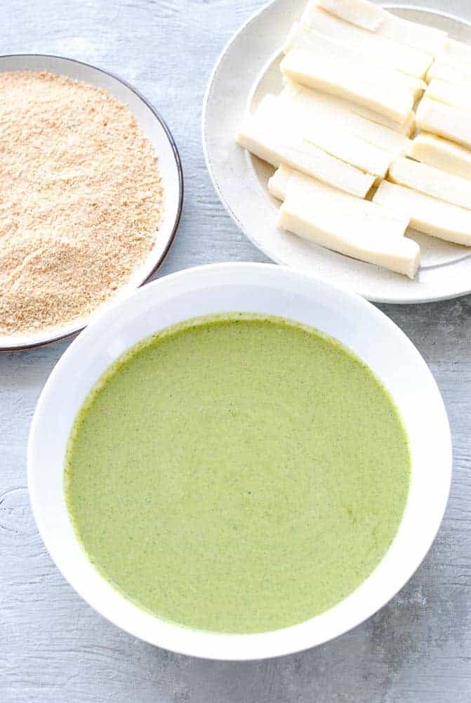 three bowls with batter, paneer cut into long strips and breadcrumbs