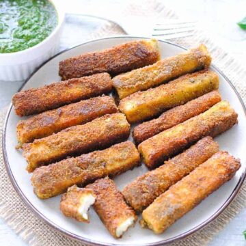 paneer fingers on a plate with green chutney in a small bowl on the side