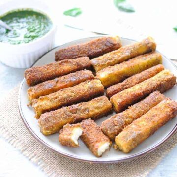 paneer fingers on a plate with green chutney on the side