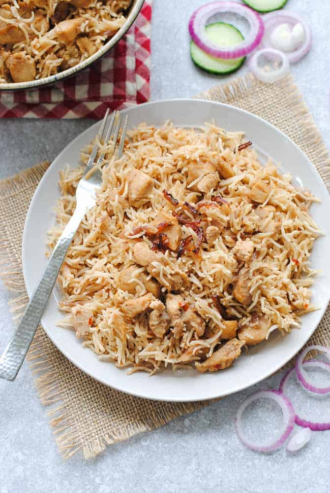 chicken pulao on a white plate with a spoon