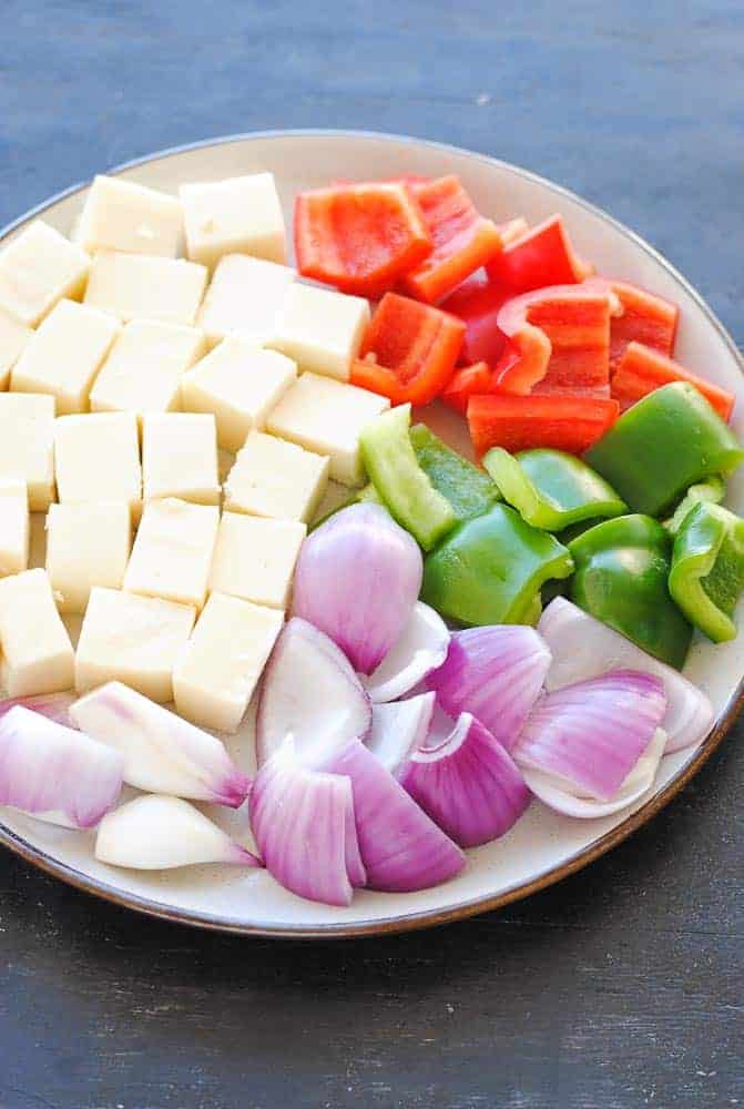 paneer cubes, onion, red and green pepper cubes on a plate