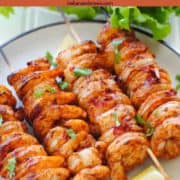 tandoori shrimp skewers on a plate with lettuce and lemon wedges