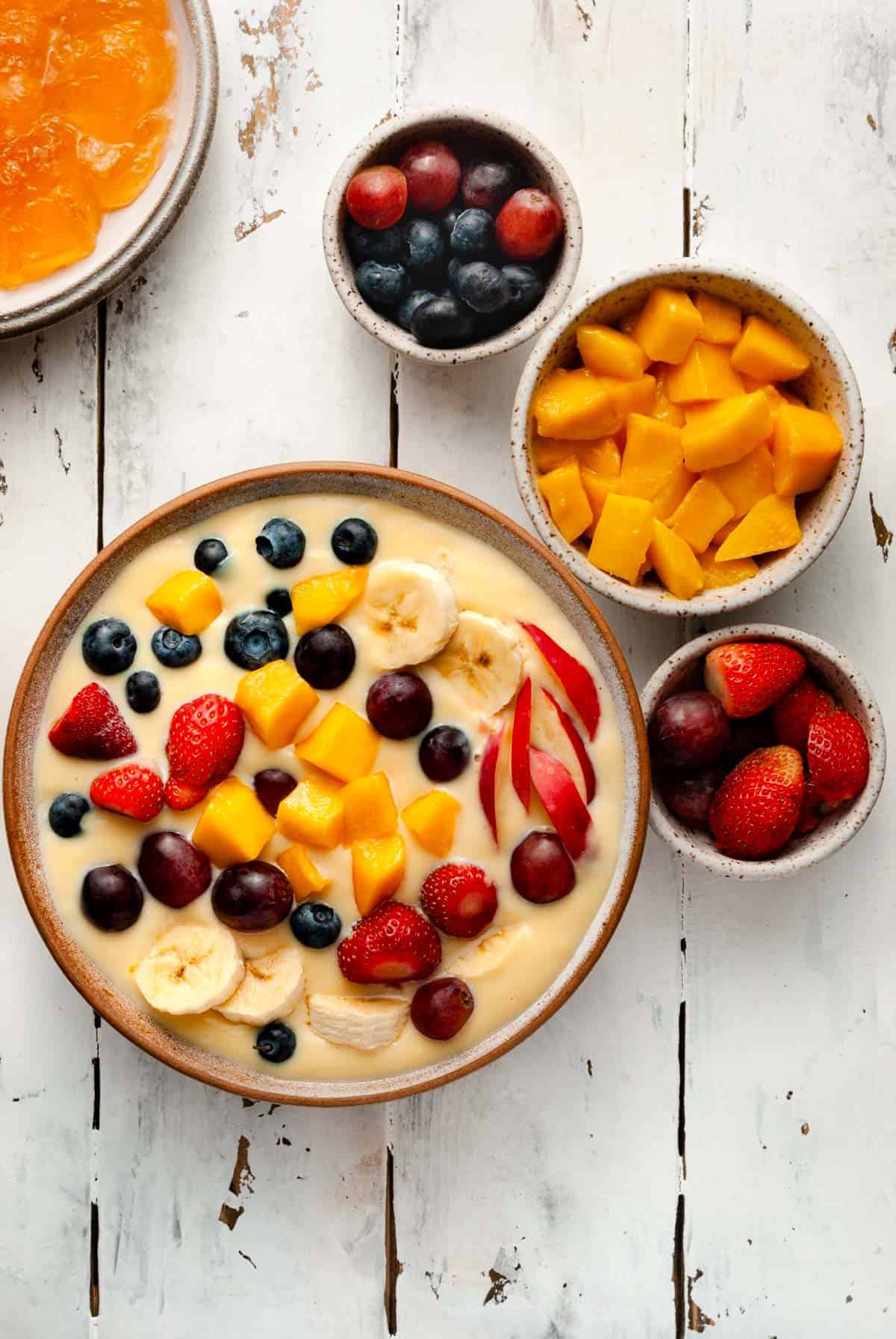 custard with strawberries, grapes, mango, apple and pomegranate in a rectangular glass dish