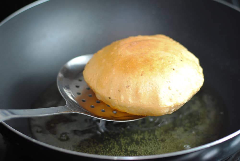 poori frying in hot oil in a wok