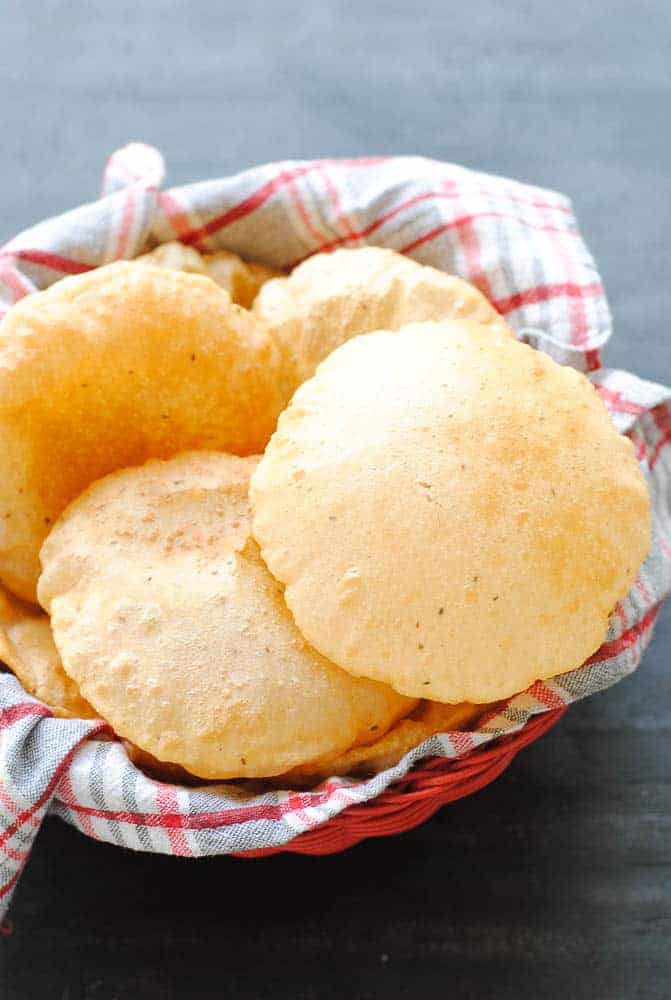 pooris on a checkered red and white cloth in a red basket