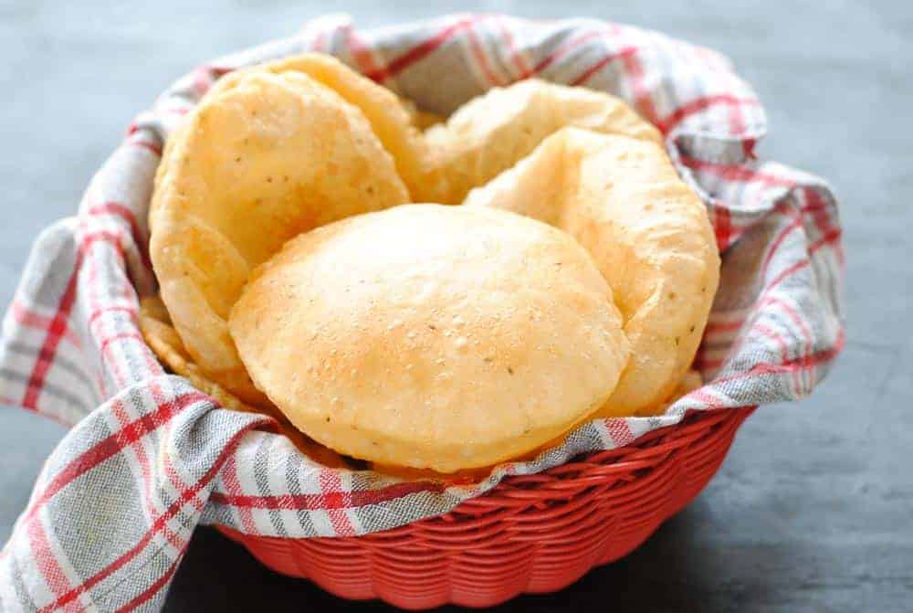 puri bread on a red and white checkered cloth in a red basket