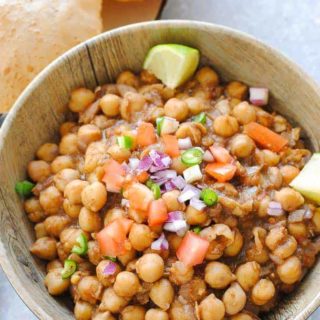 chole (chickpeas) in a bowl with pooris (Indian bread) on the side