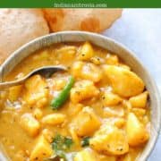potato curry in a bowl with poori (fried indian bread) on the side