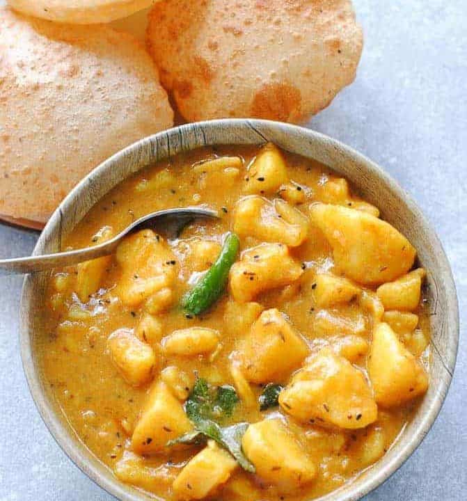 aloo curry in a bowl with poori on the side