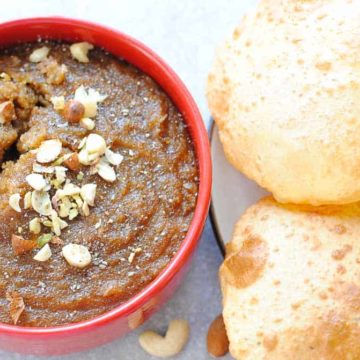 rava sheera in a red bowl with poori on the side