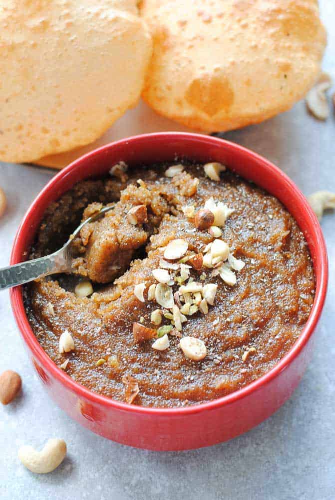 rava sheera in a red bowl with pooris