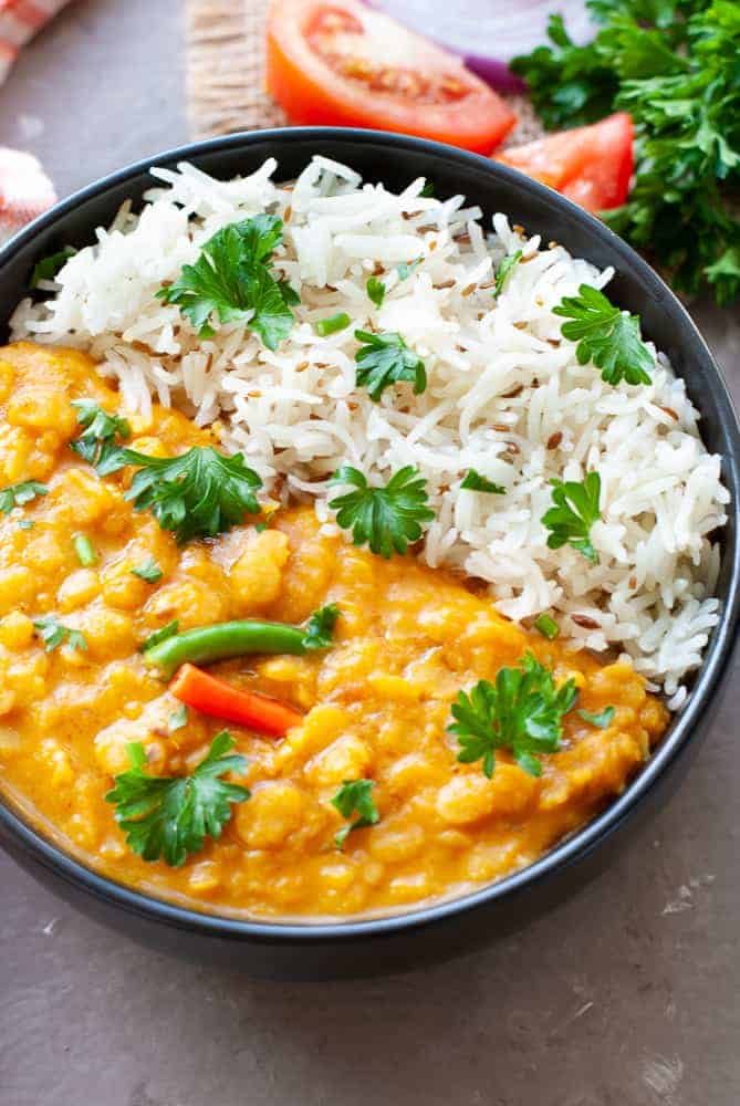toor dal and jeera rice in a bowl with a topping of parsley and green chillies