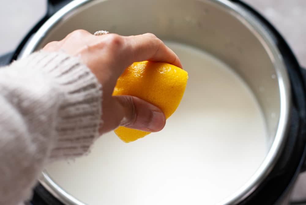 a lemon being squeezed into milk in the instant pot