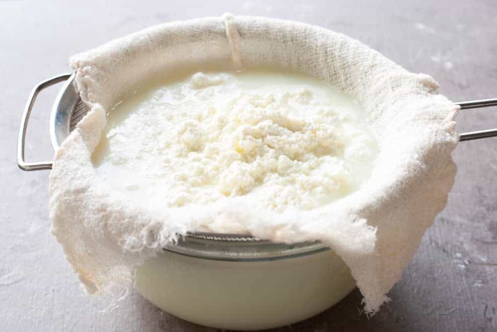 paneer straining in a colander over a bowl