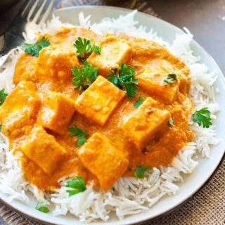 paneer butter masala over white rice in a plate