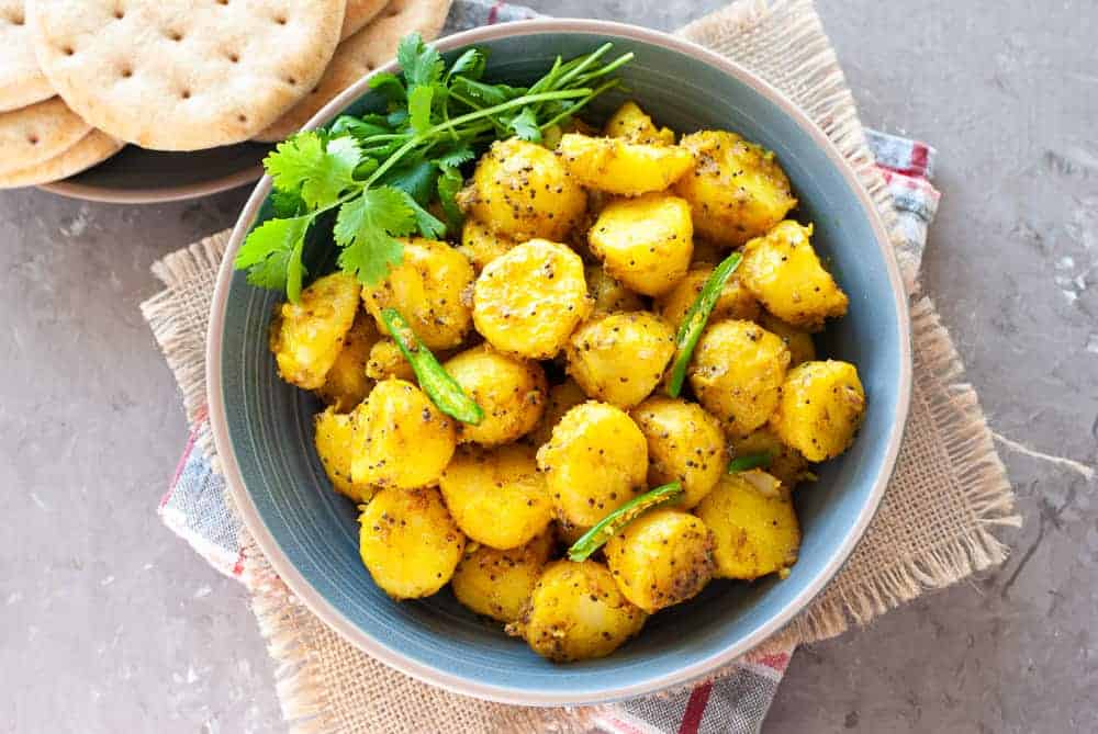 Bombay potatoes in a bowl with naan on the side