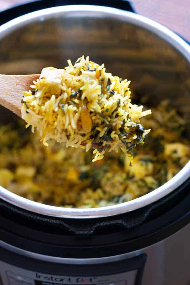 palak pulao on a wooden spoon over instant pot