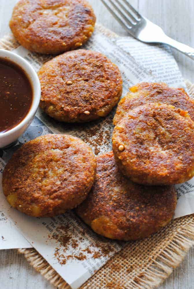 aloo tikki on some newspaper with a bowl of imli chutney