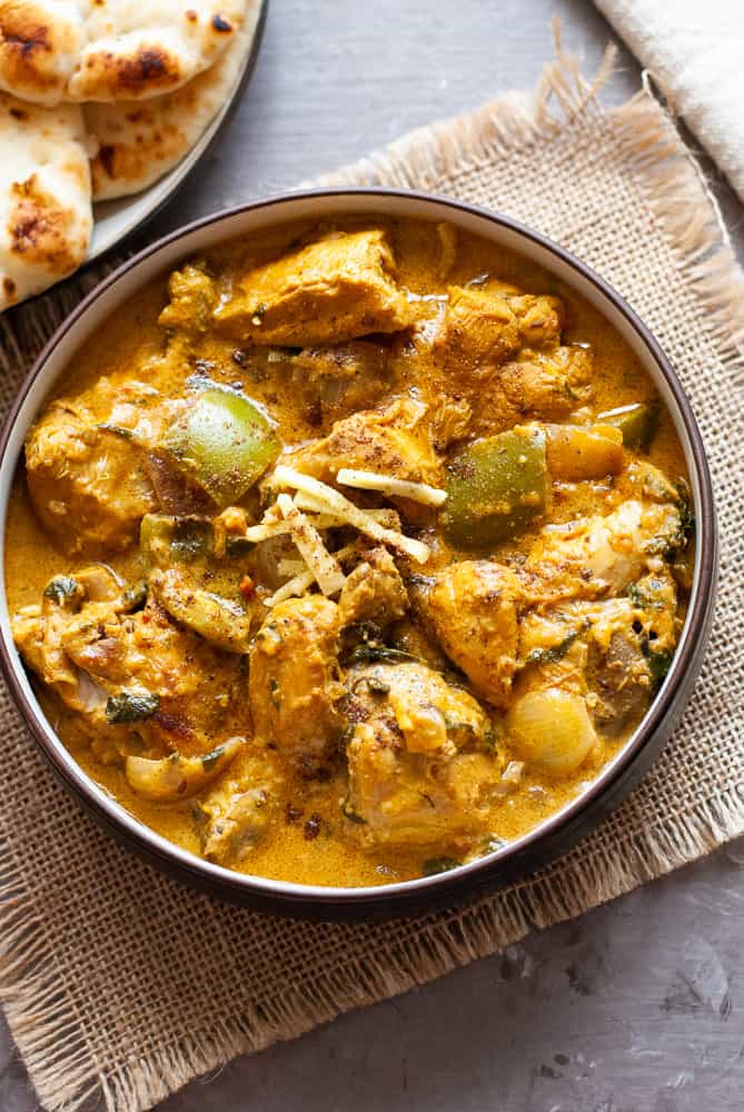 chicken patiala in bowl with naan bread in background