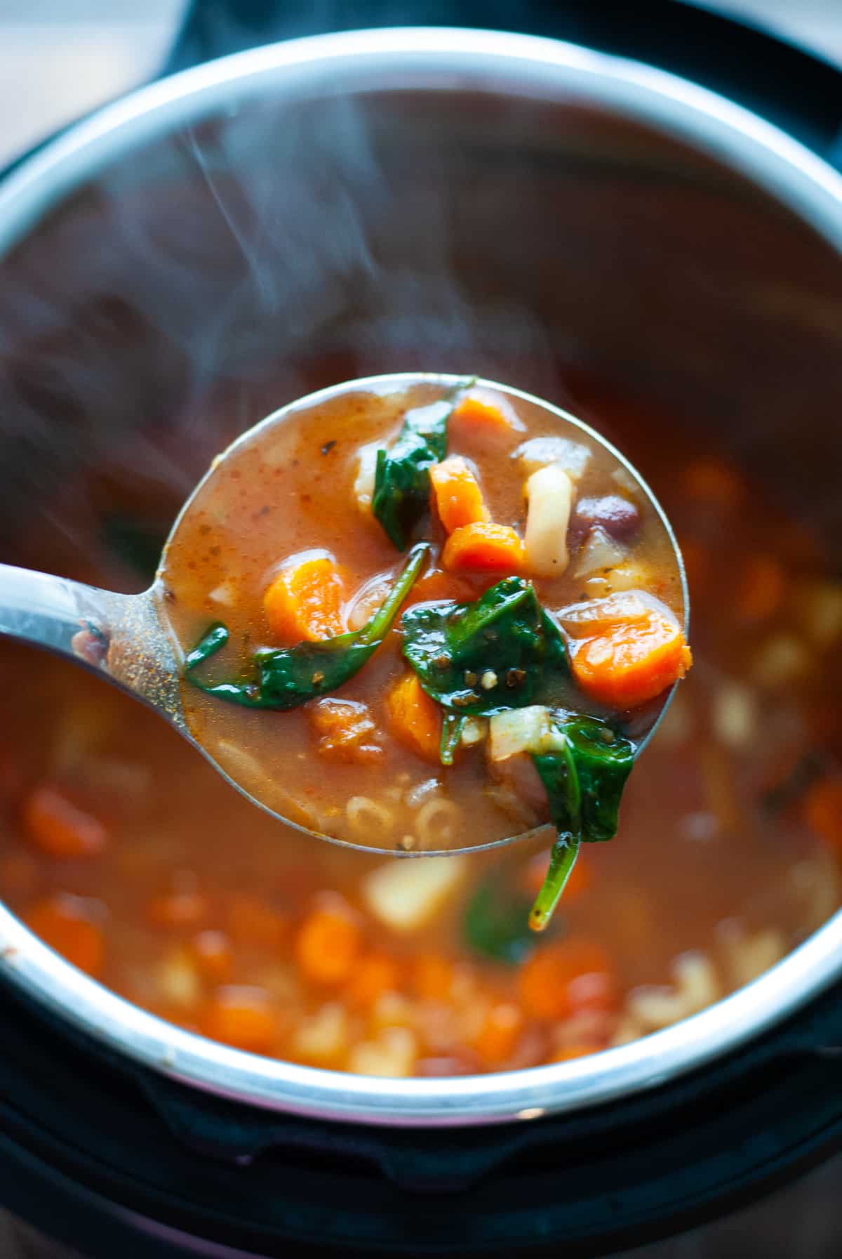minestrone soup in a big spoon poised over the instant pot