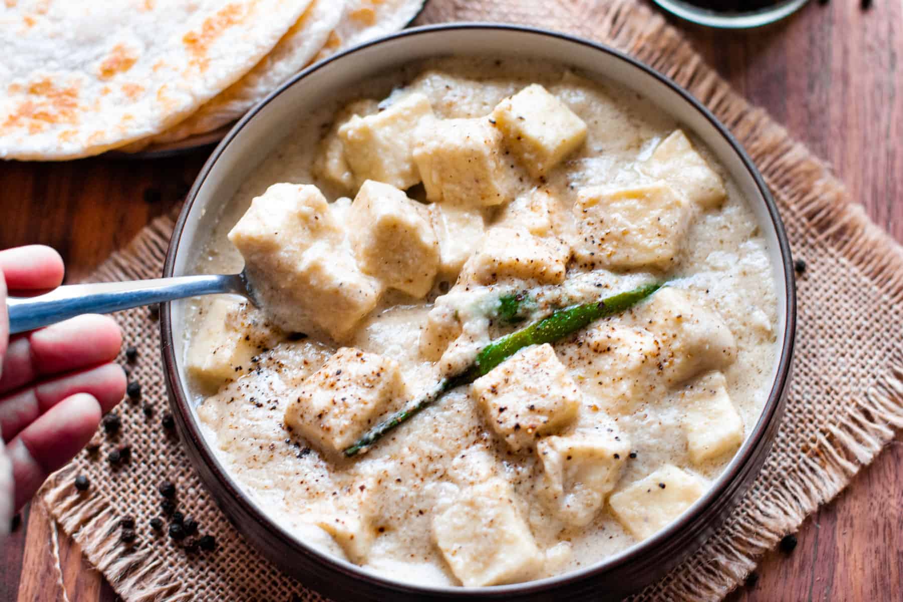 paneer in white sauce in bowl with a spoon