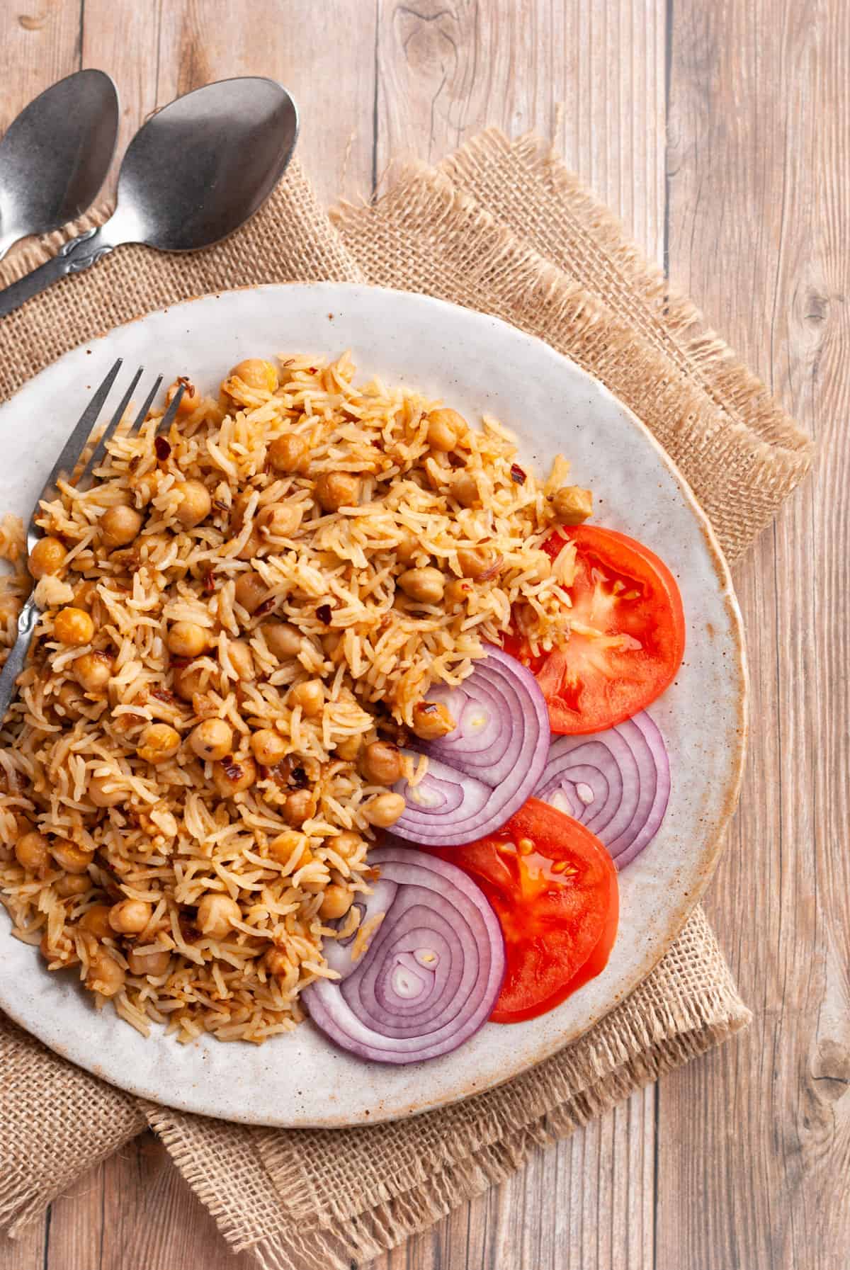Chana Pulao in plate with sliced onions and tomatoes