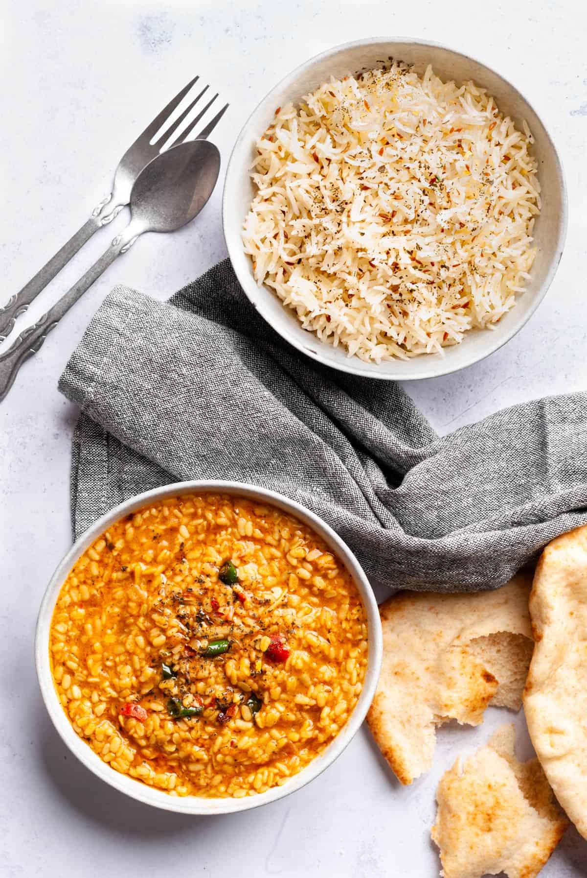 maash dal in bowl, rice in bowl and naan pieces on the side with a napkin