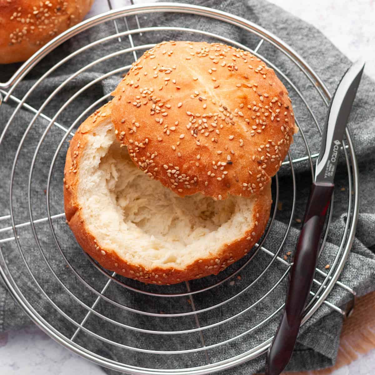 bread bowl on a round cooling rack with a knife on the side