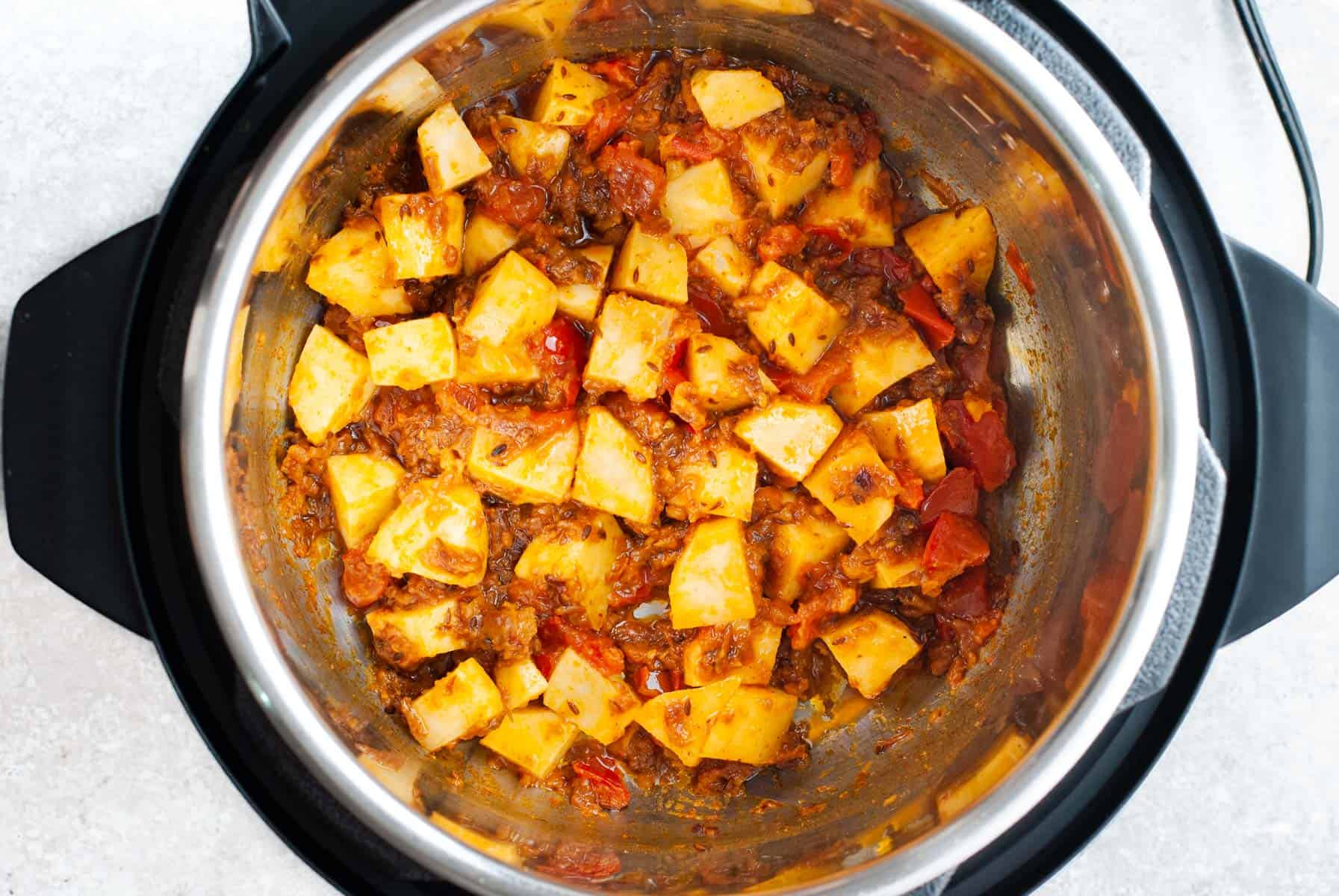 cubed potatoes mixed with onion tomato masala in instant pot