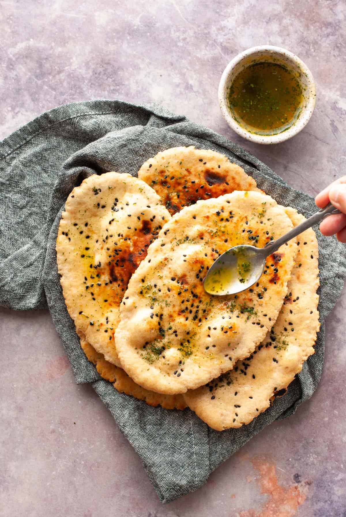 drizzling ghee with a spoon on naan bread