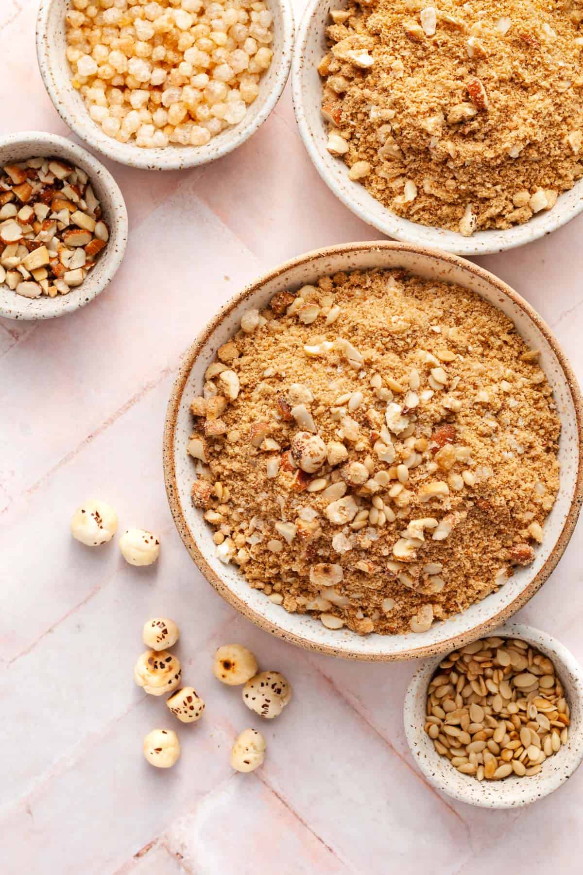 Panjeeri in a bowl with  dry fruit in small bowls around it.