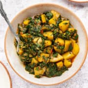 aloo palak in a bowl with spoon