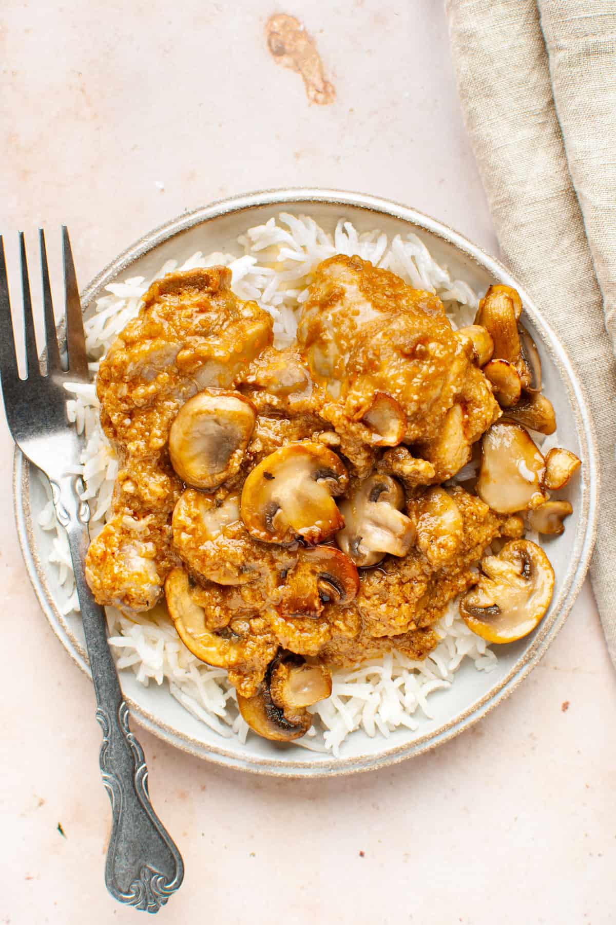Chicken mushroom curry over rice in a plate with a fork.