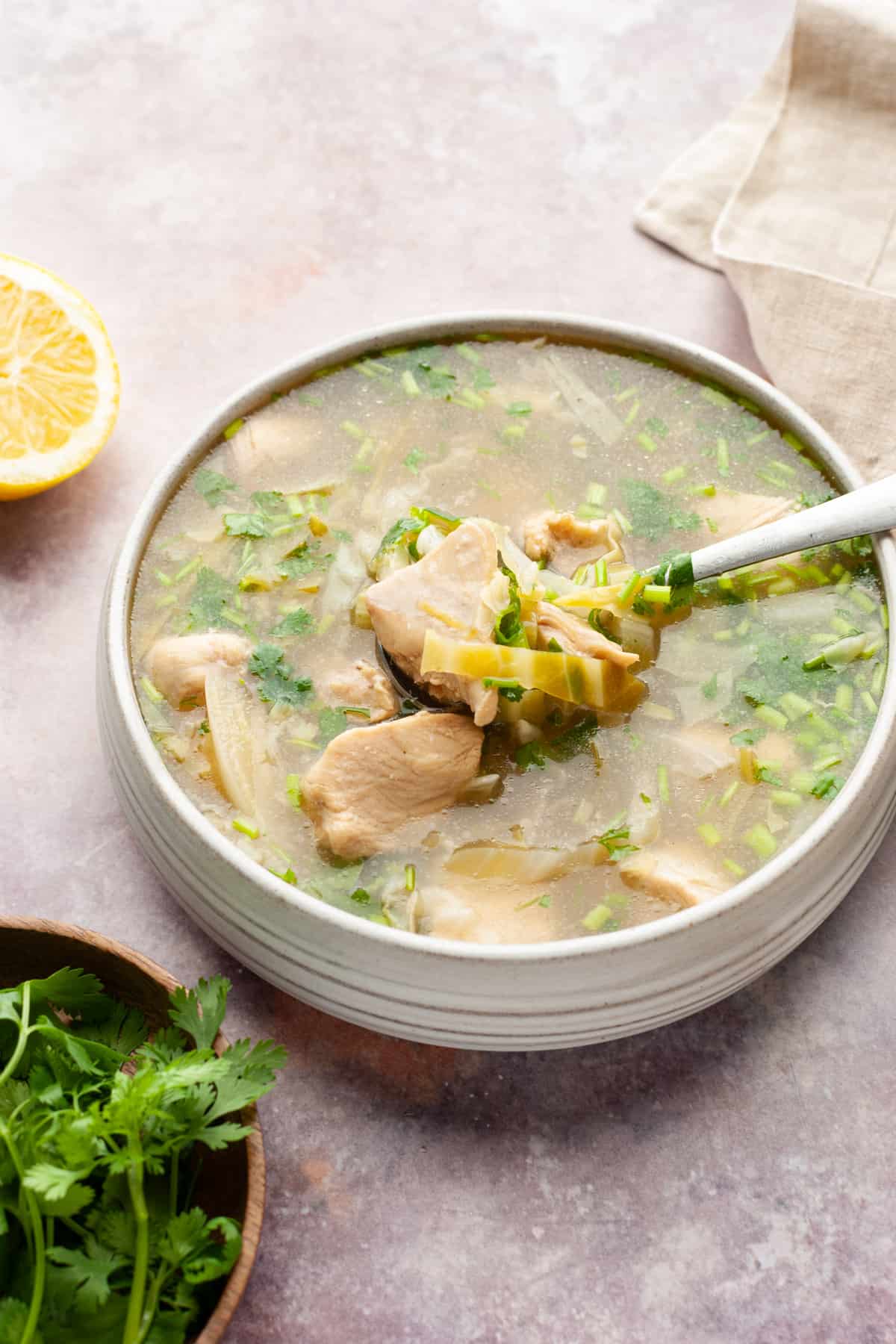 Chicken lemon coriander soup in a bowl with a spoon. 