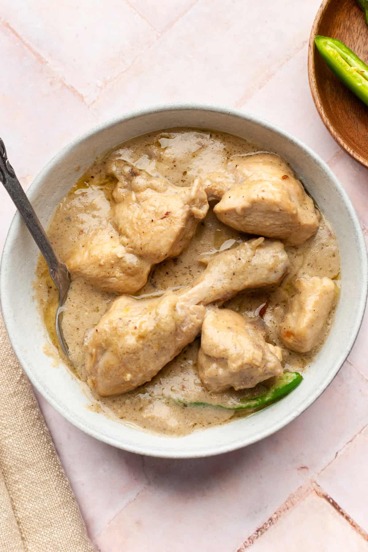White chicken karahi in a bowl with a spoon. 