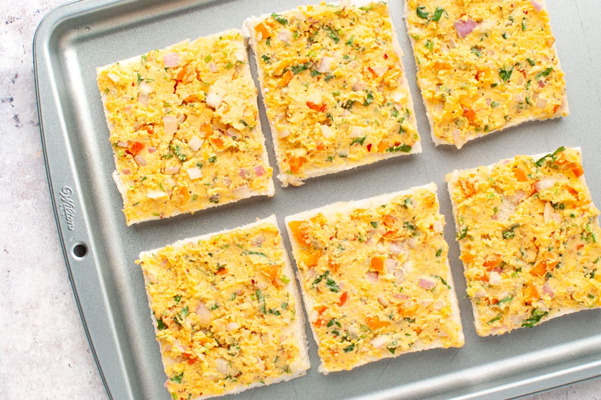 Chilli cheese toast squares (uncooked) on a baking tray.