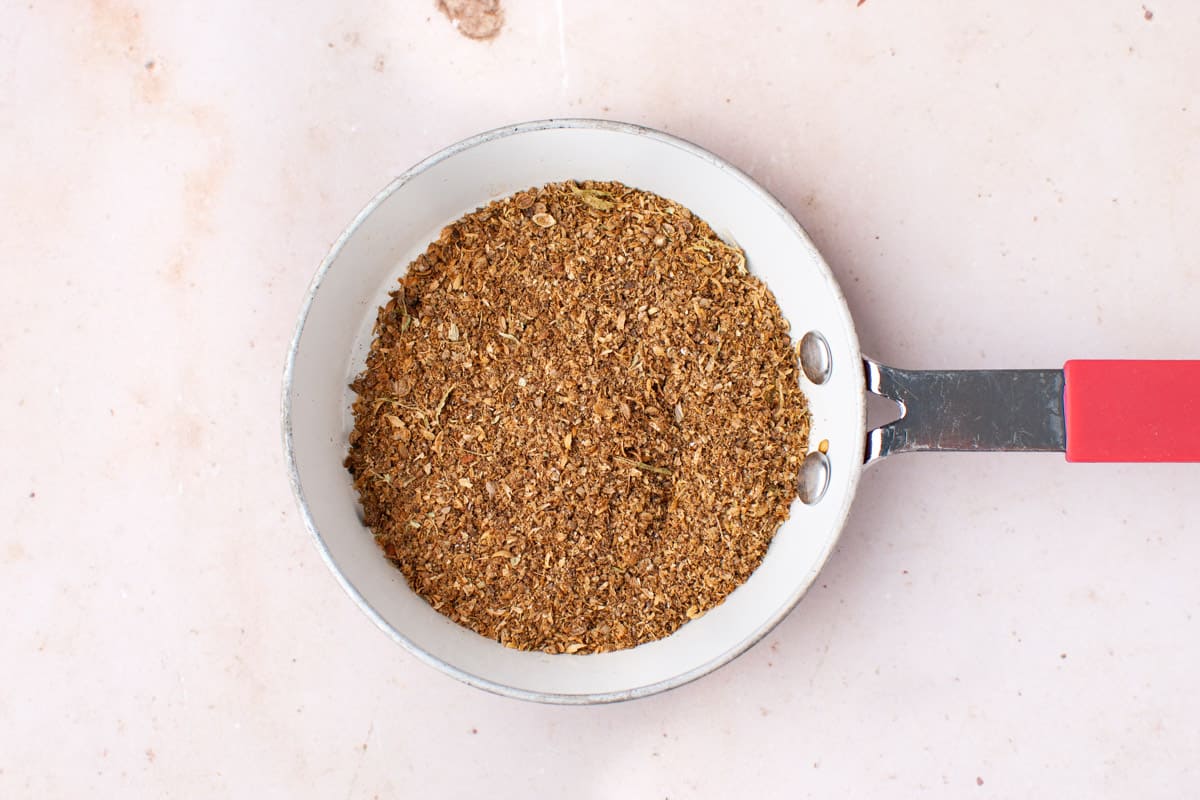 Ground spice mixture in a small frypan.